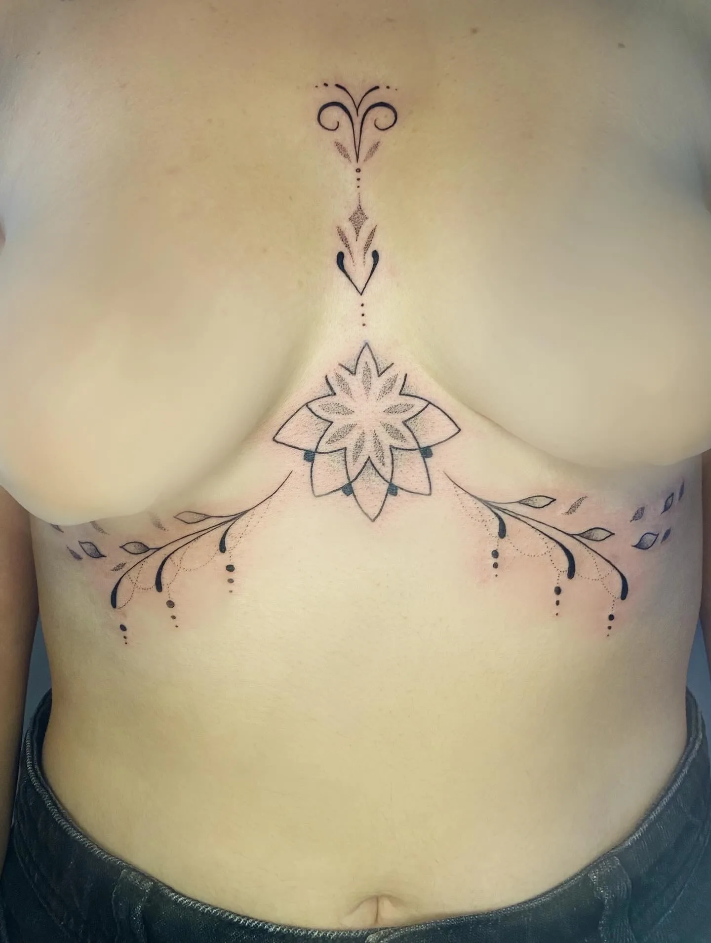 Tatouage lotus et branches ornementales sternum fine line — Annahata Tattoo